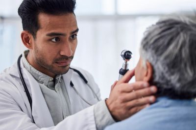 Doctor examining elderly patient's ear.
