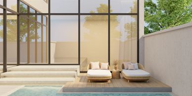 Modern patio with a small pool and two cushioned lounge chairs on a wooden deck.