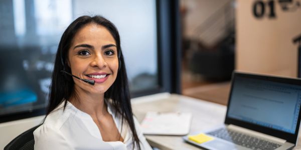 Smiling woman wearing a headset at her workspace.
