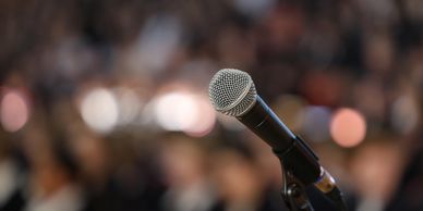 Close-up of a microphone with blurred audience in the background.