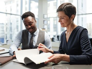 Two professionals reviewing documents together in a bright office.