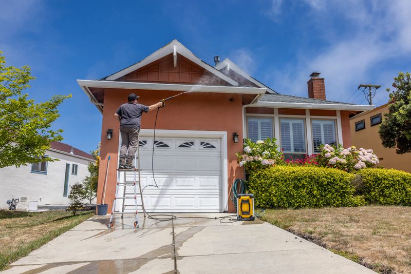 High quality stock photo of a middle aged man power washing a single-family home.