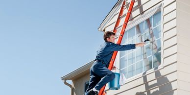 Window Cleaner on ladder cleaning exterior window on a house