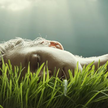 Person peacefully resting face-down in lush green grass.