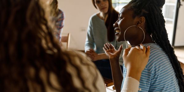 A supportive group listens as a woman shares her story with a smile.
