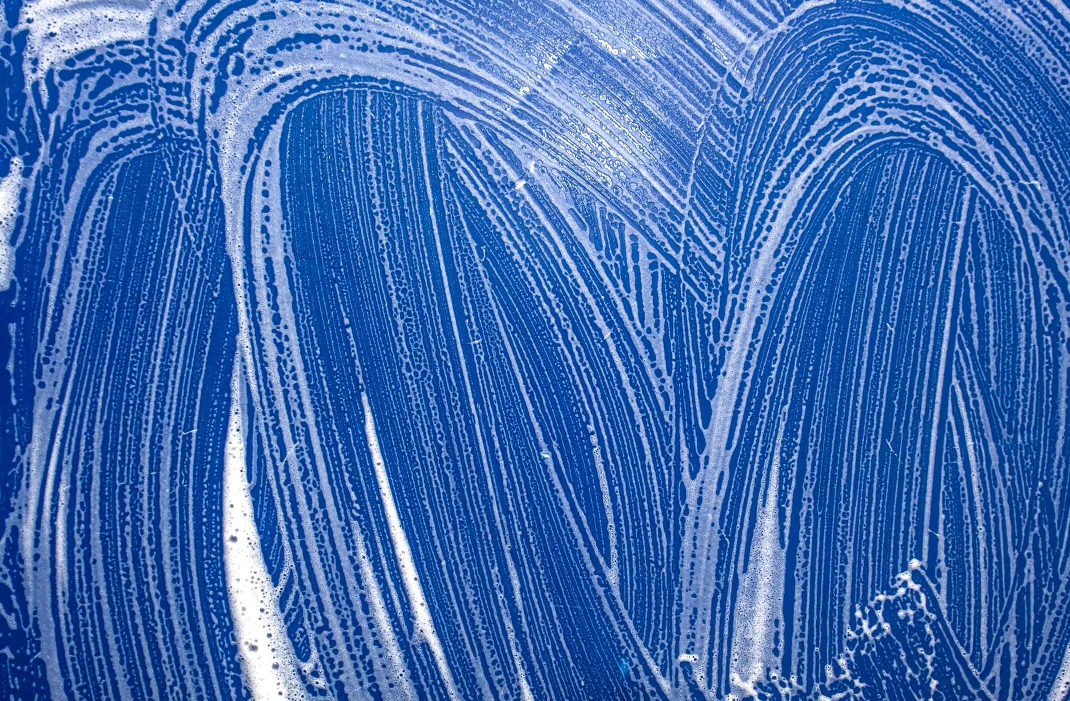 Blue glass surface covered with soap suds and streaks.