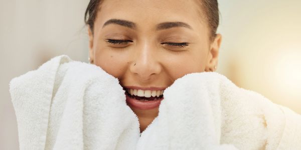 Smiling woman wrapped in a soft white towel, enjoying a cozy moment.