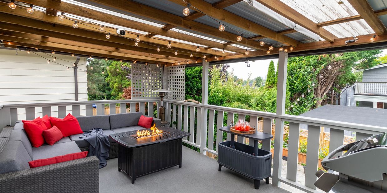 Cozy outdoor patio with fire pit, string lights, and comfortable seating.