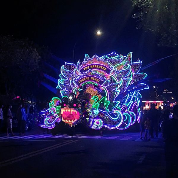 Colorful illuminated dragon float glowing brightly at night parade.
