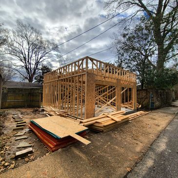 Wooden frame structure of a building under construction on a cloudy day.