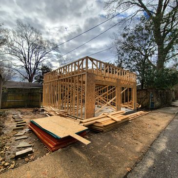 Wooden framework of a house under construction on a cloudy day.