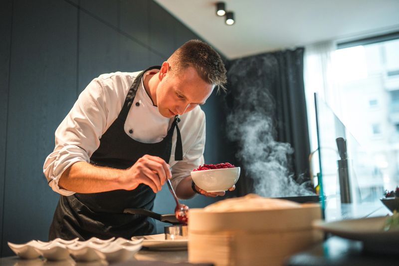 A professional chef, wearing an apron, preparing a variety of gourmet dishes for an unforgettable bachelorette dinner. Witness his precision and skill in action.