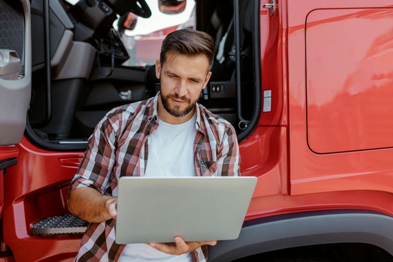 Male Truck Driver Using Laptop on a Parking Lot