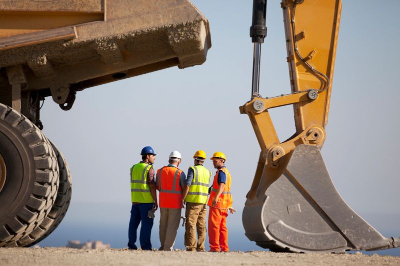 Workers talking by machinery in quarry