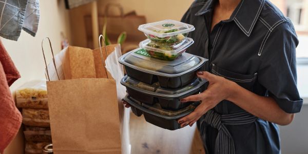 Person holding stacked takeout food containers.
