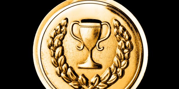 Close-up of a gold medal with a trophy and laurel wreath design.