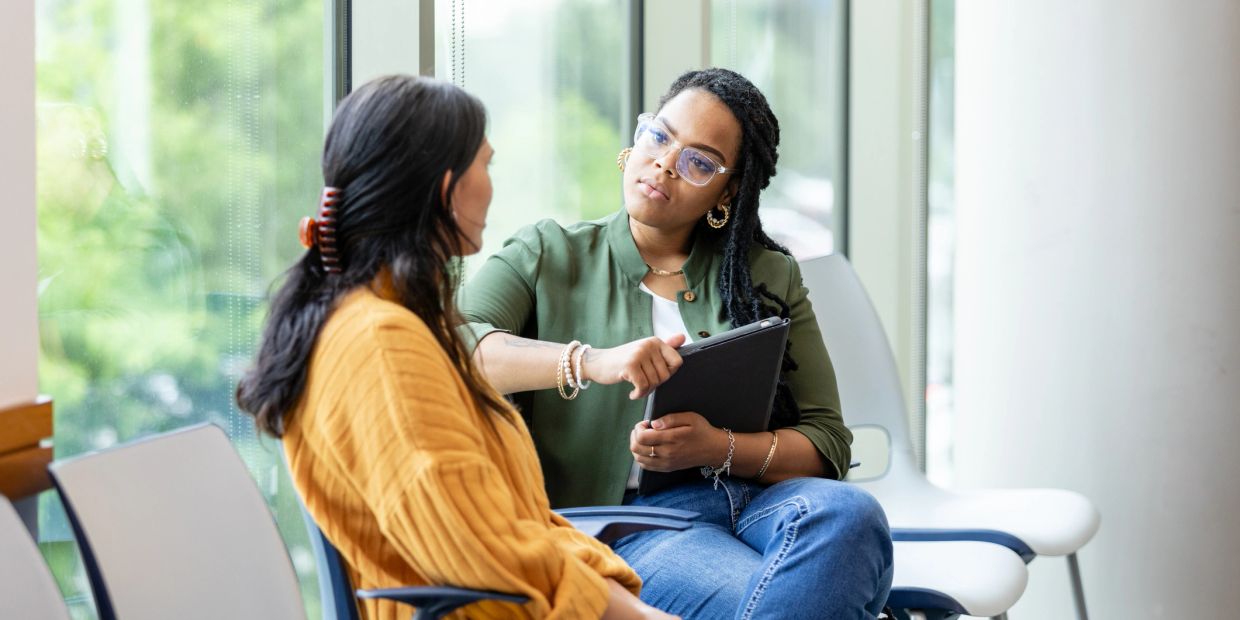 Two women engaged in a serious conversation in a waiting area.
