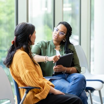Two women having a discussion in a bright modern office.