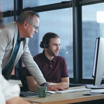 A team collaborating at a computer in a modern office with headsets.