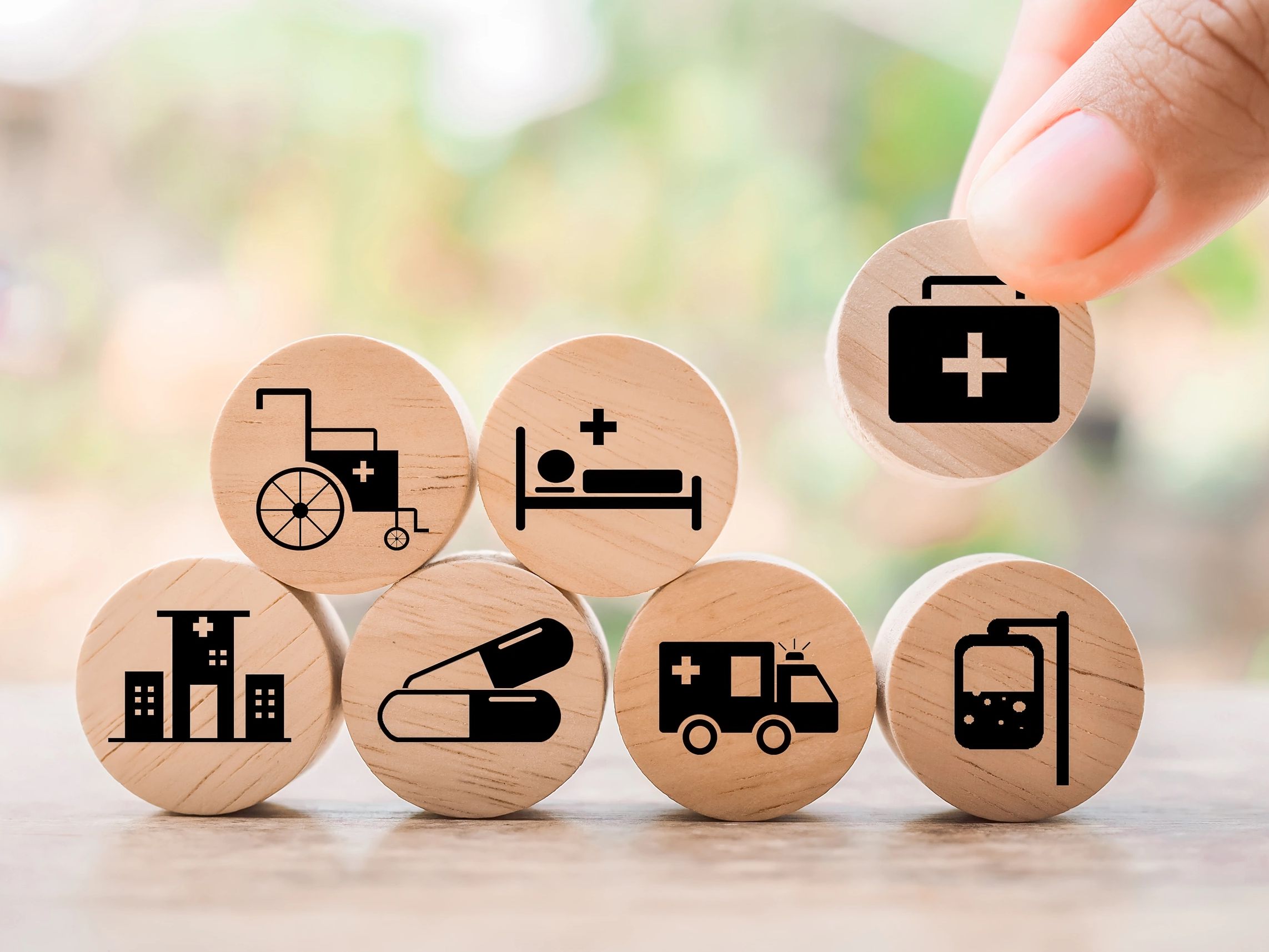 Wooden blocks with healthcare symbols, including wheelchair, hospital bed, and ambulance.
