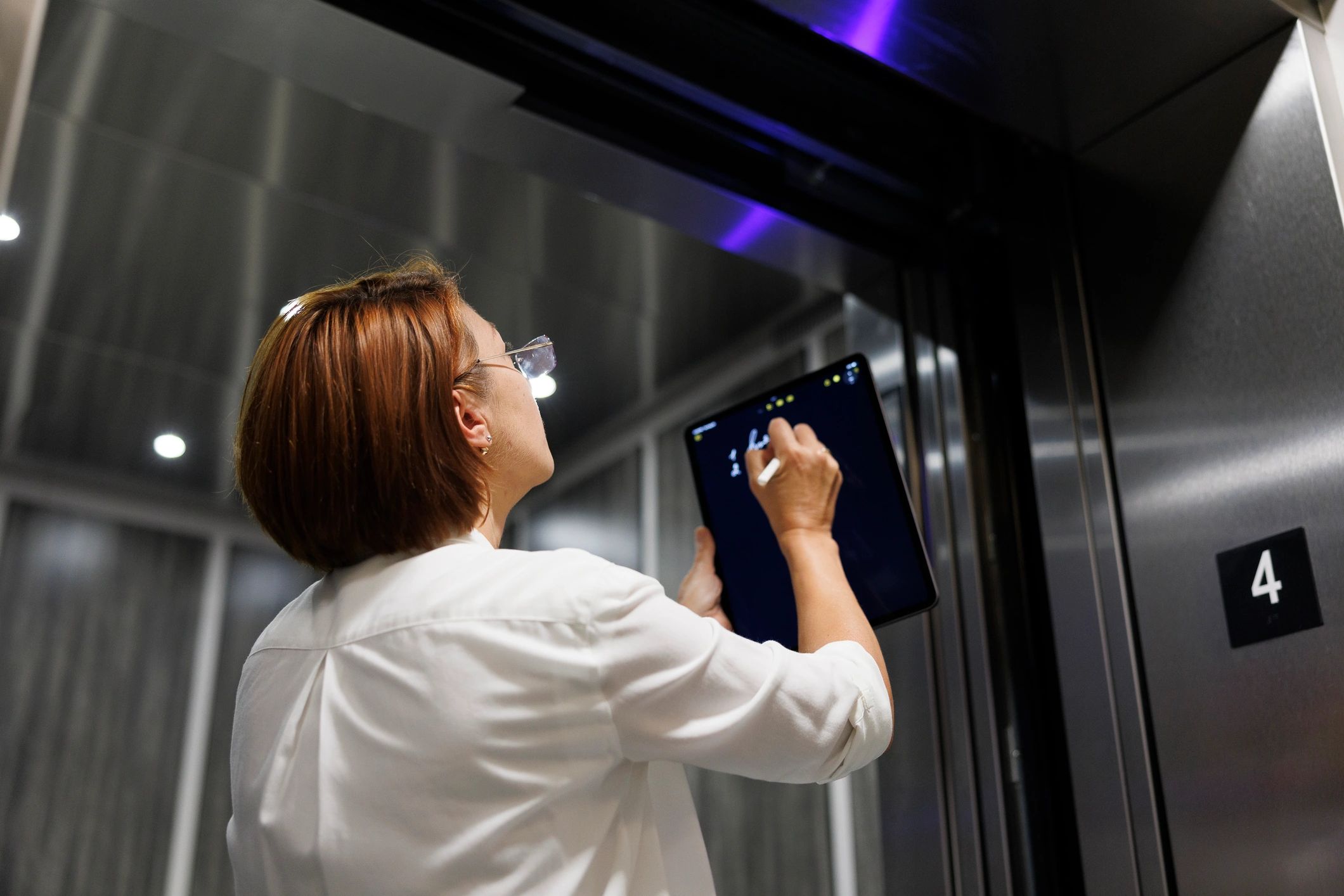 Woman using tablet near elevator number 4.
