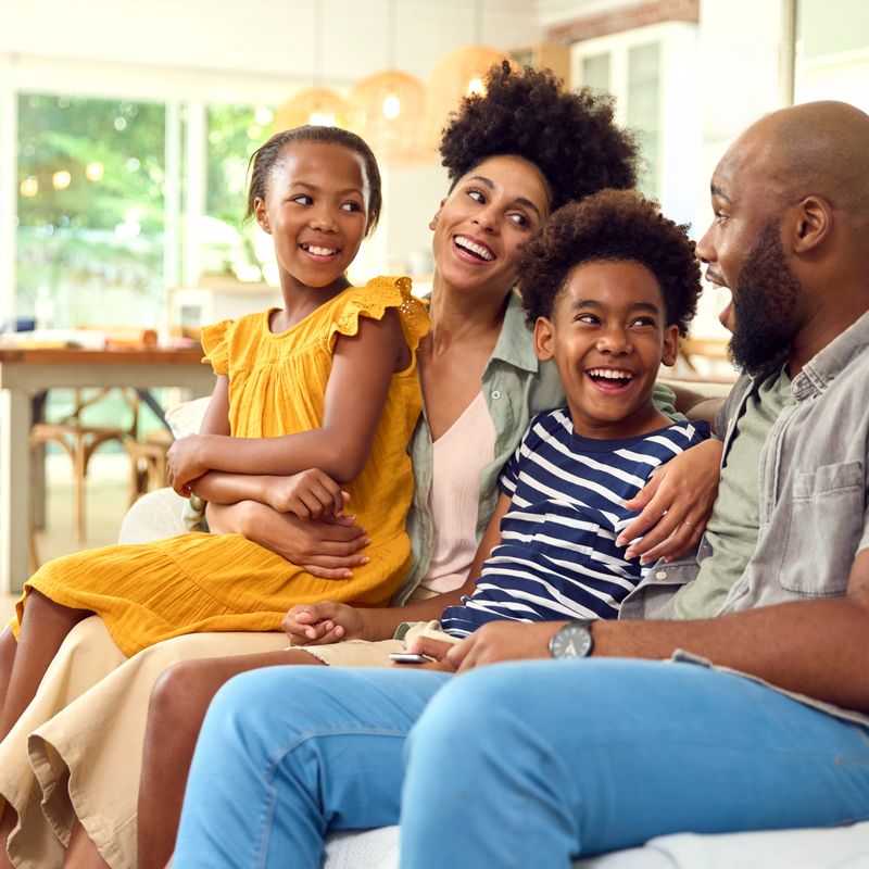 Family At Home Sitting On Sofa Together Streaming Show Or Movie To TV