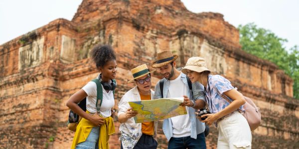 Group of tourists looking at a map near an ancient brick structure.
