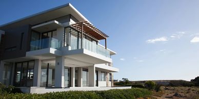 Modern house with glass balconies under a clear blue sky.