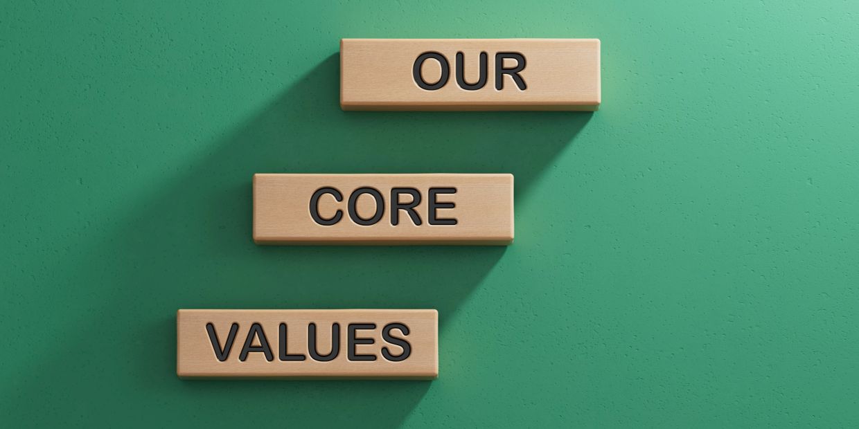 Wooden blocks spell 'OUR CORE VALUES' on green surface.