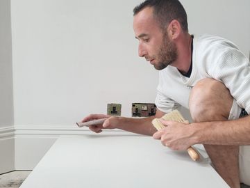 Man installing or inspecting electrical outlets on a wall.