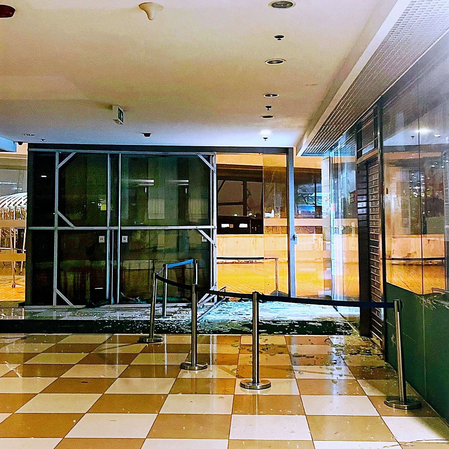 Broken glass and barricades in a mall corridor.