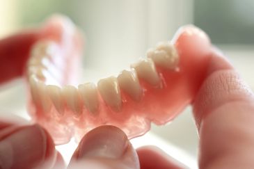 Close-up of dentures held by hands.