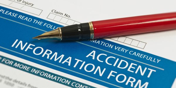A red fountain pen resting on an accident information form.