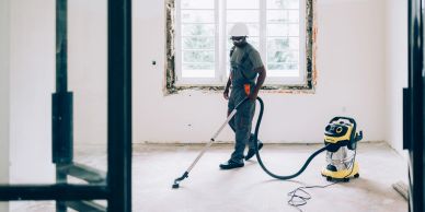 Worker vacuuming floor in an empty room.