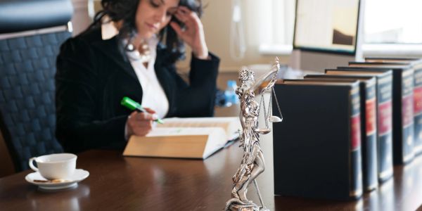 A lawyer working at her desk with legal books and a statue.