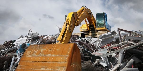 Yellow excavator working at a scrapyard.