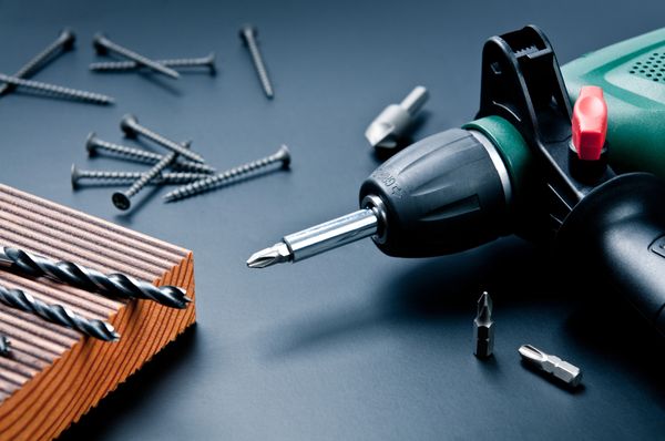 Electric drill with drill bits and screws on a table.