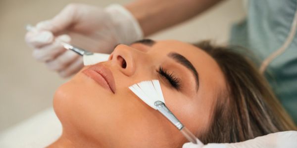 Woman receiving a facial treatment with brushes.