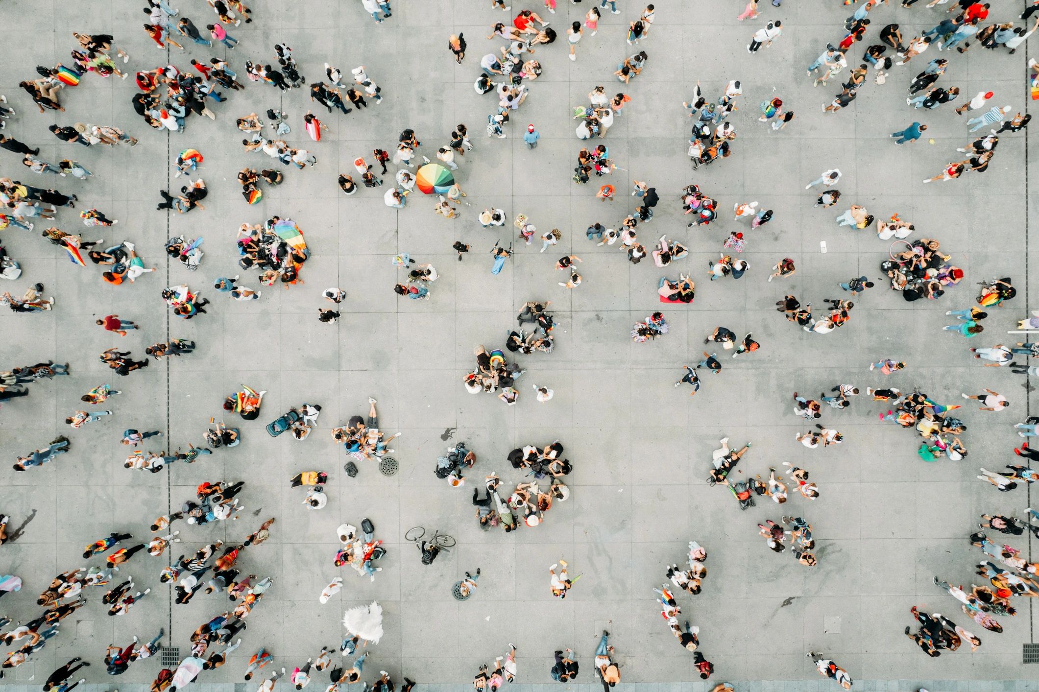 Aerial view of a large space with people moving across the pavement or gathering in small groups