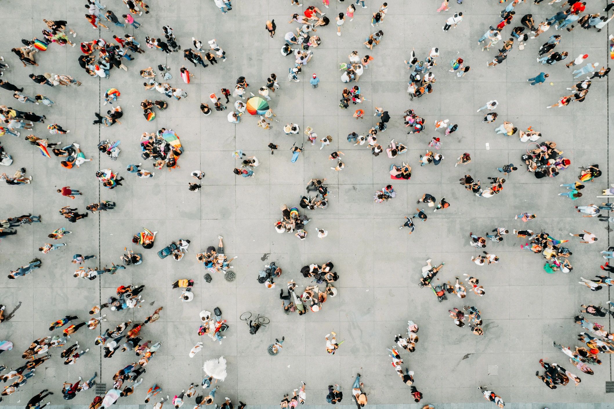 Aerial view of a large open square with pedestrians, cyclists and people gathering in small groups.