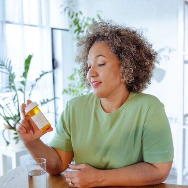 Woman reading medication label at home.