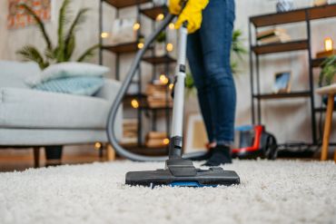 Person vacuuming a carpet in a cozy living room.