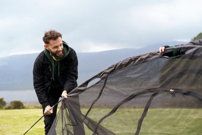 Man setting up a tent outdoors.