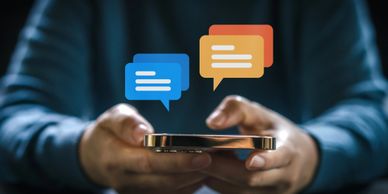 Image of a person typing with two thumbs on their mobile phone, with blue and orange conversation bu