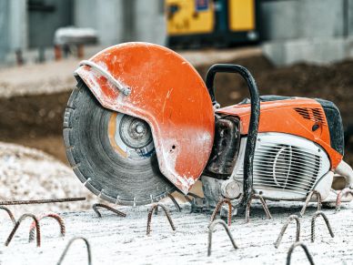 Orange concrete saw on construction site.