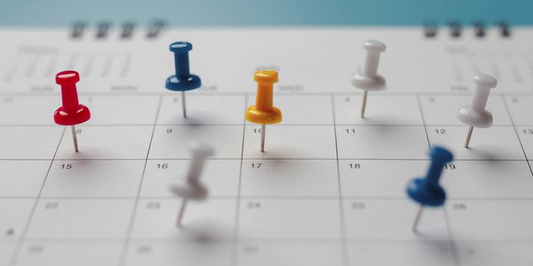 Colorful push pins marking specific dates on a calendar.
