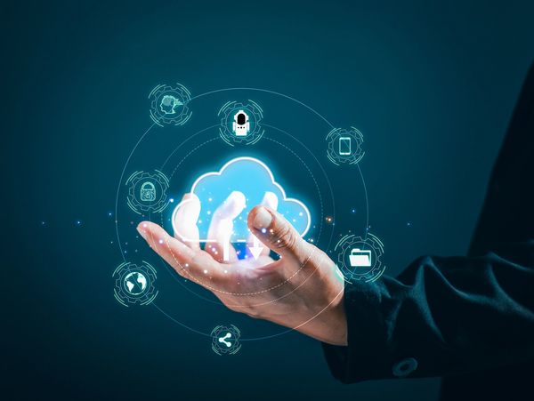 Hand holding a glowing cloud icon with digital technology symbols around it.