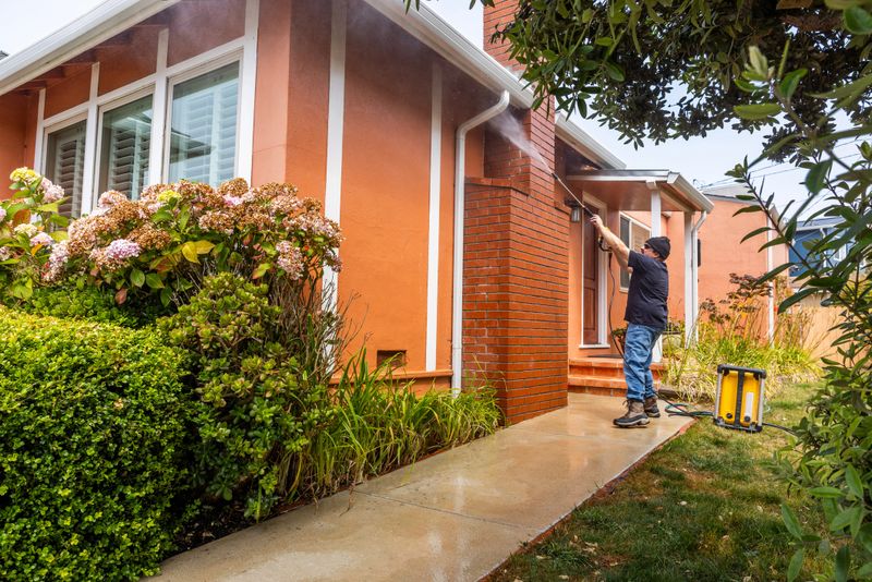High quality stock photo of a middle aged man power washing a single-family home.