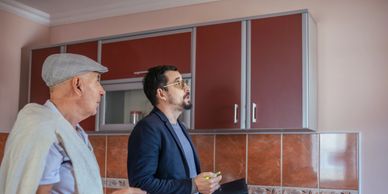 Two men inspecting kitchen cabinets.