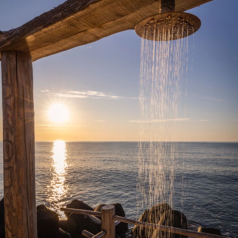 An outdoor shower overlooking the sea at sunset